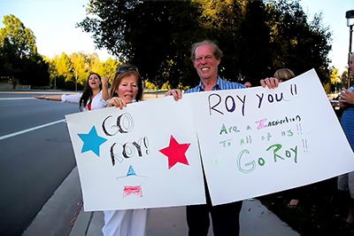 Wiegand’s parents, Bridget and Roy (a trombone player), await their son at the finish line proudly holding signs of encouragement and congratulations.