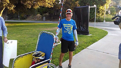 He made it! Wiegand crosses the finish line with stroller in tow — during the run, he rolled with the stroller with which he gave rides to kids along the way.